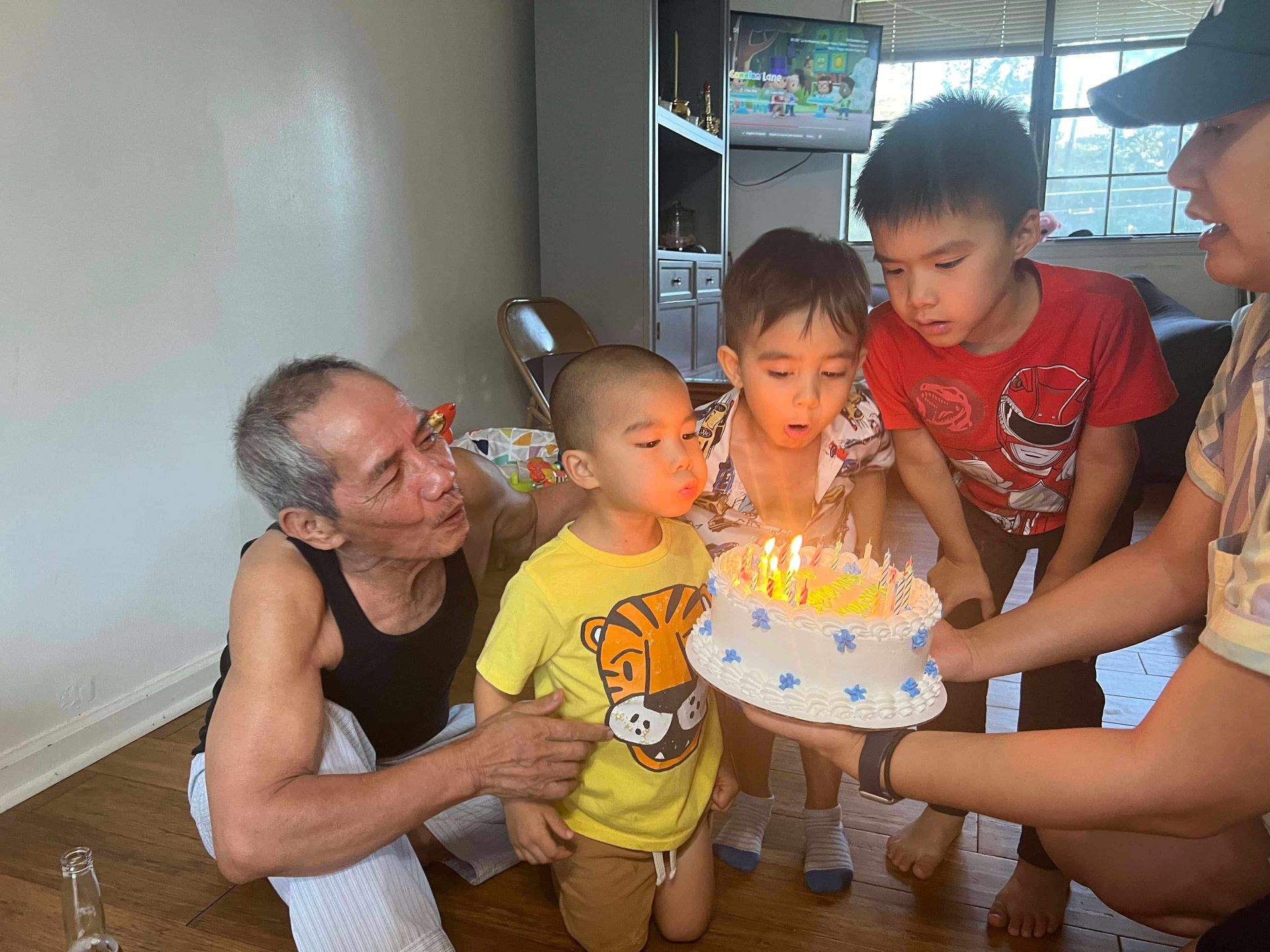 Grandfather and grandchildren blowing out birthday candles together