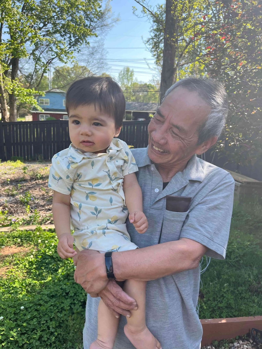 Grandfather holding his grandchild in the backyard
