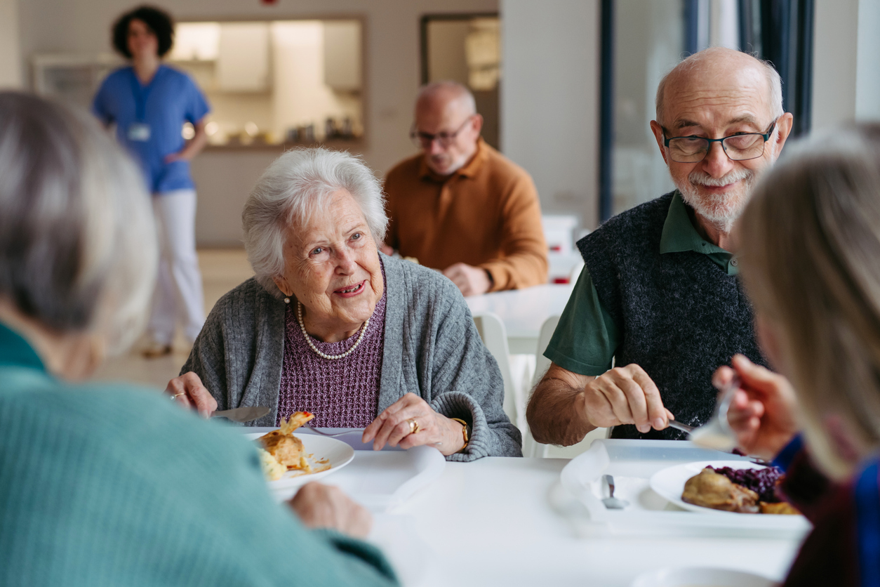 Seniors enjoying a meal together in a warm community setting